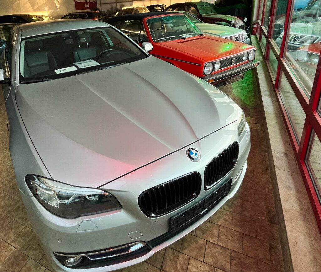 Showroom des HOCO Automarkts am Schwabenring 104 in Minden im Herbst 2025, mit einem silbernen BMW, einem VW Golf 1 Cabrio Mercedes Coupe Oldtimer und einem Citroën 2CV.